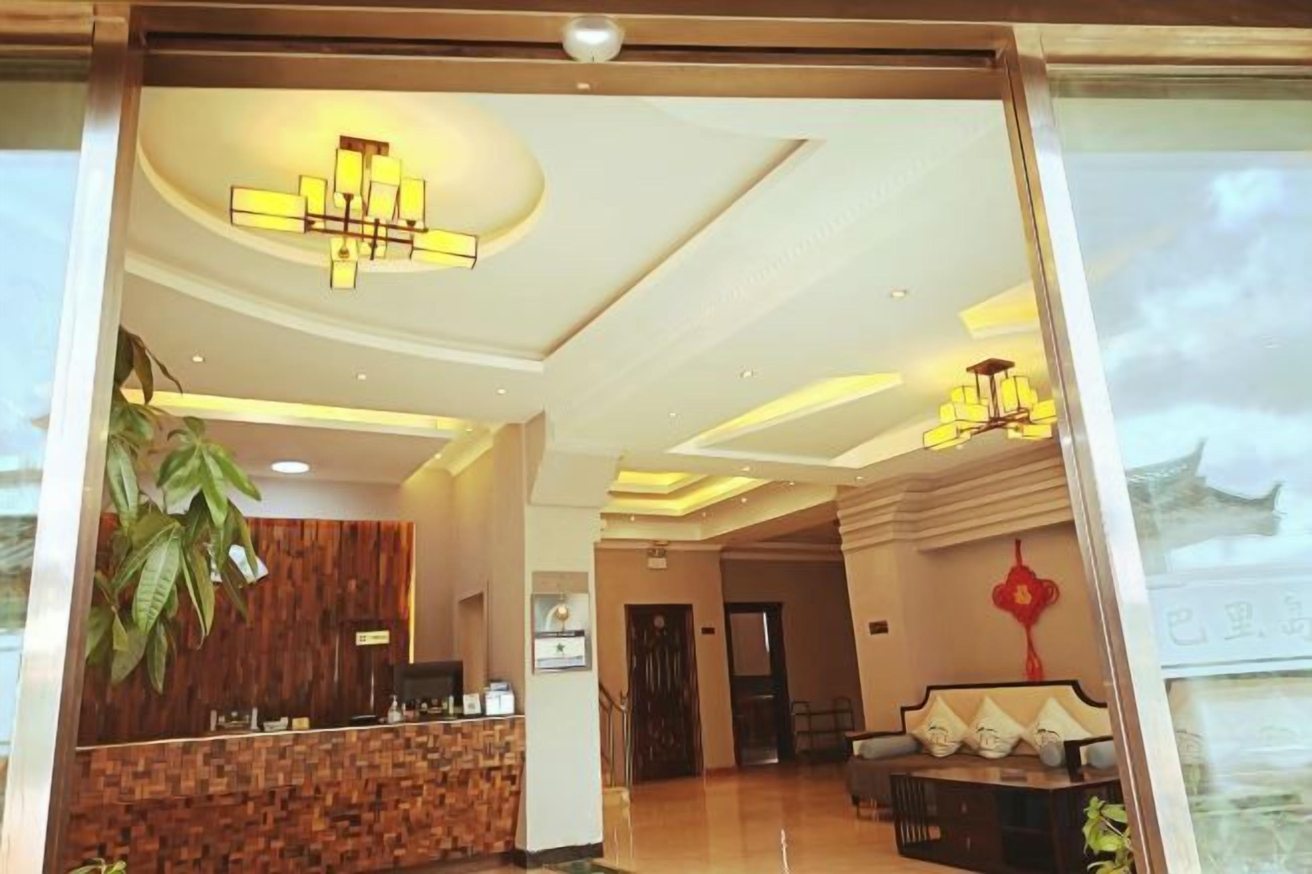 Vestíbulo de hotel con una recepción, una planta grande y una zona de estar con un elemento decorativo rojo.