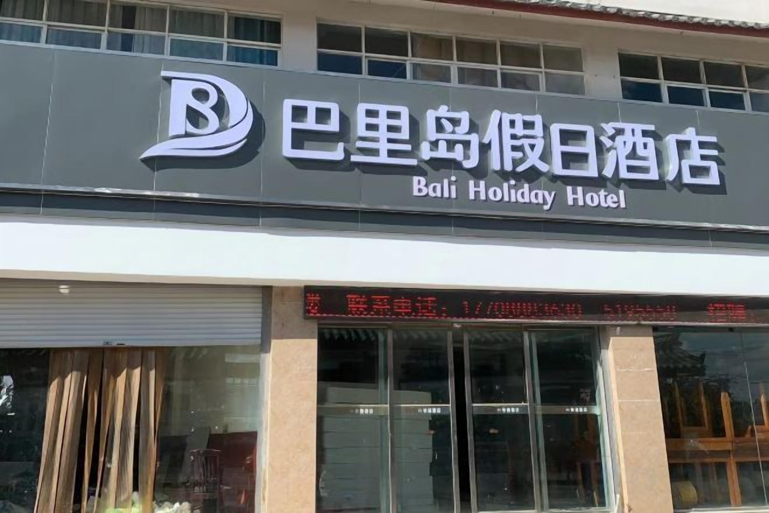 A hotel sign with the name 'Bali Holiday Hotel' and a digital display with text.