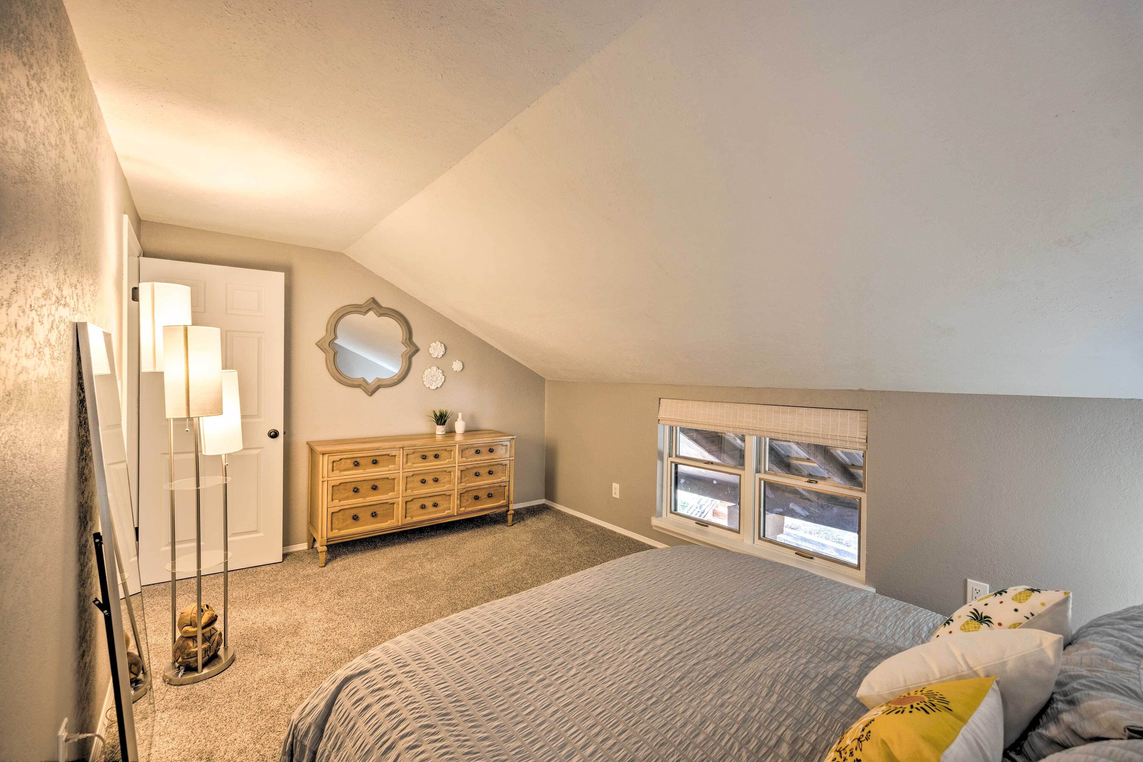A bedroom with a bed, dresser, and a window with blinds.