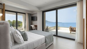 Ein modernes Schlafzimmer mit einem großen Bett, einem Schreibtisch und Blick aufs Meer.