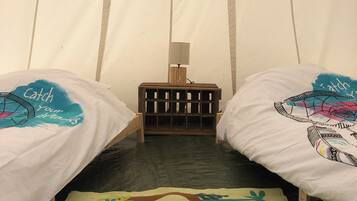 Una habitación acogedora con dos camas, un atrapasueños colgante y una alfombra colorida.