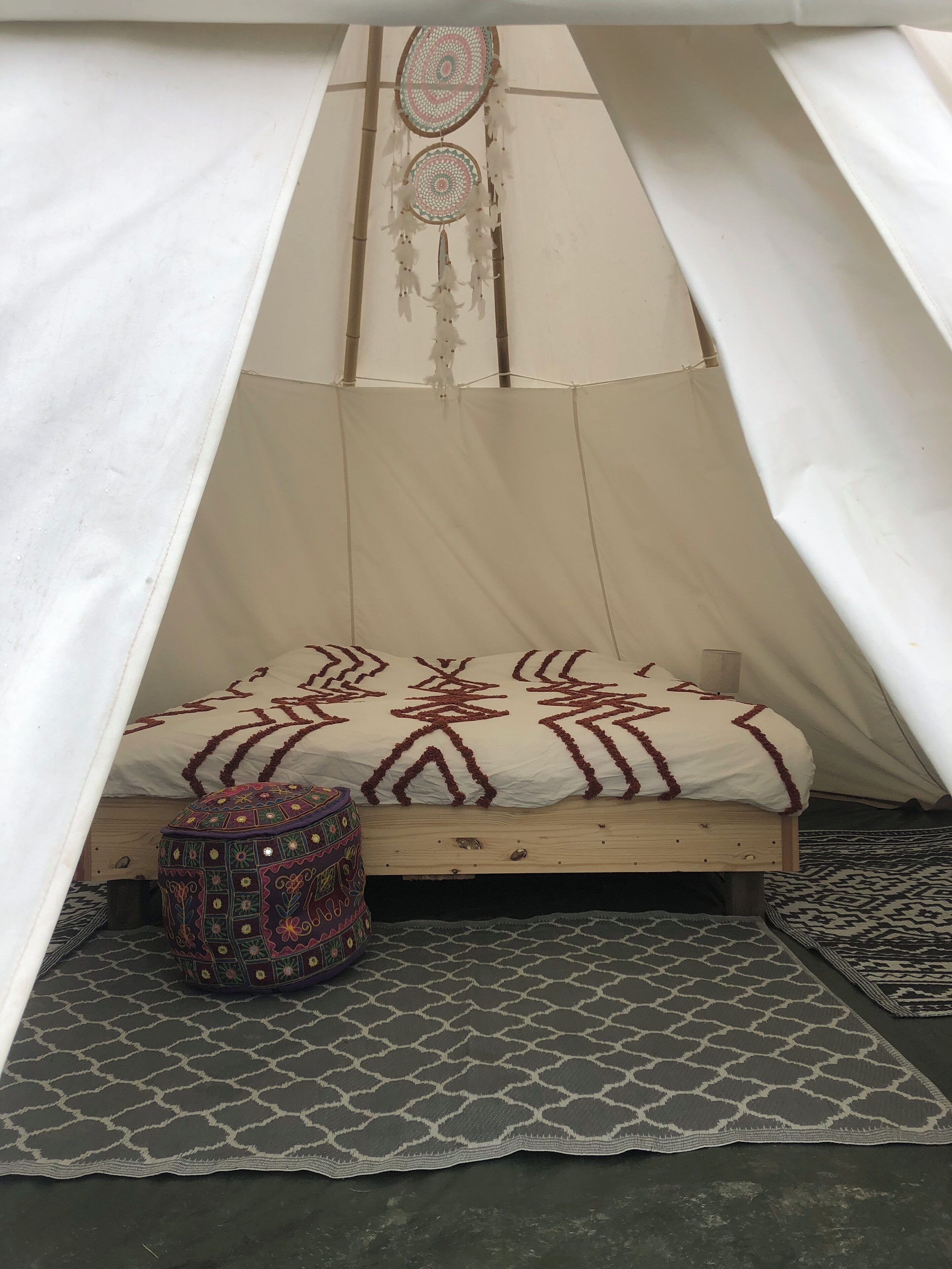 A cozy tent with a bed, a patterned rug, and a decorative pillow.