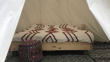 A cozy tent with a bed, a patterned rug, and a decorative pillow.