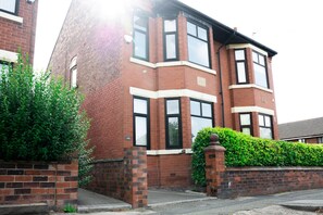 A two-story brick house with a corner entrance, a visible number '170', and a well-maintained hedge. - 4 Luxury Ensuite Bedrooms, Games & Arcade Room (Manchester)