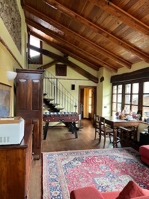 Relax in this spacious room with a high ceiling, featuring a large cabinet, foosball table, and dining area.