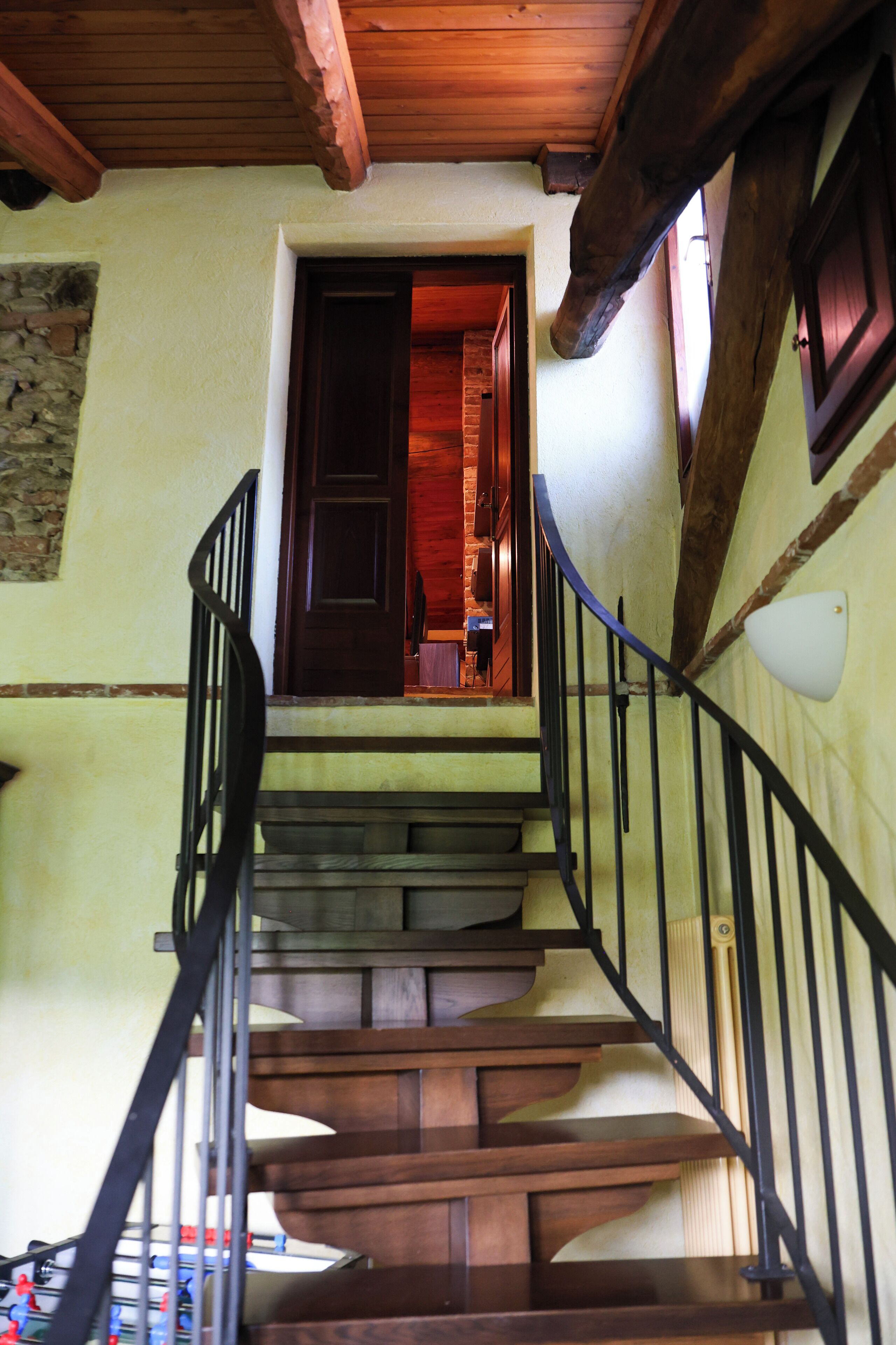 A wooden staircase with a black railing leading to a door.