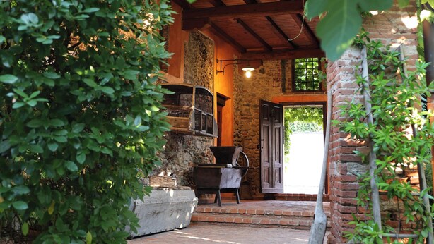 A stone pathway leading to a rustic wooden building with a brick exterior and a stone wall.