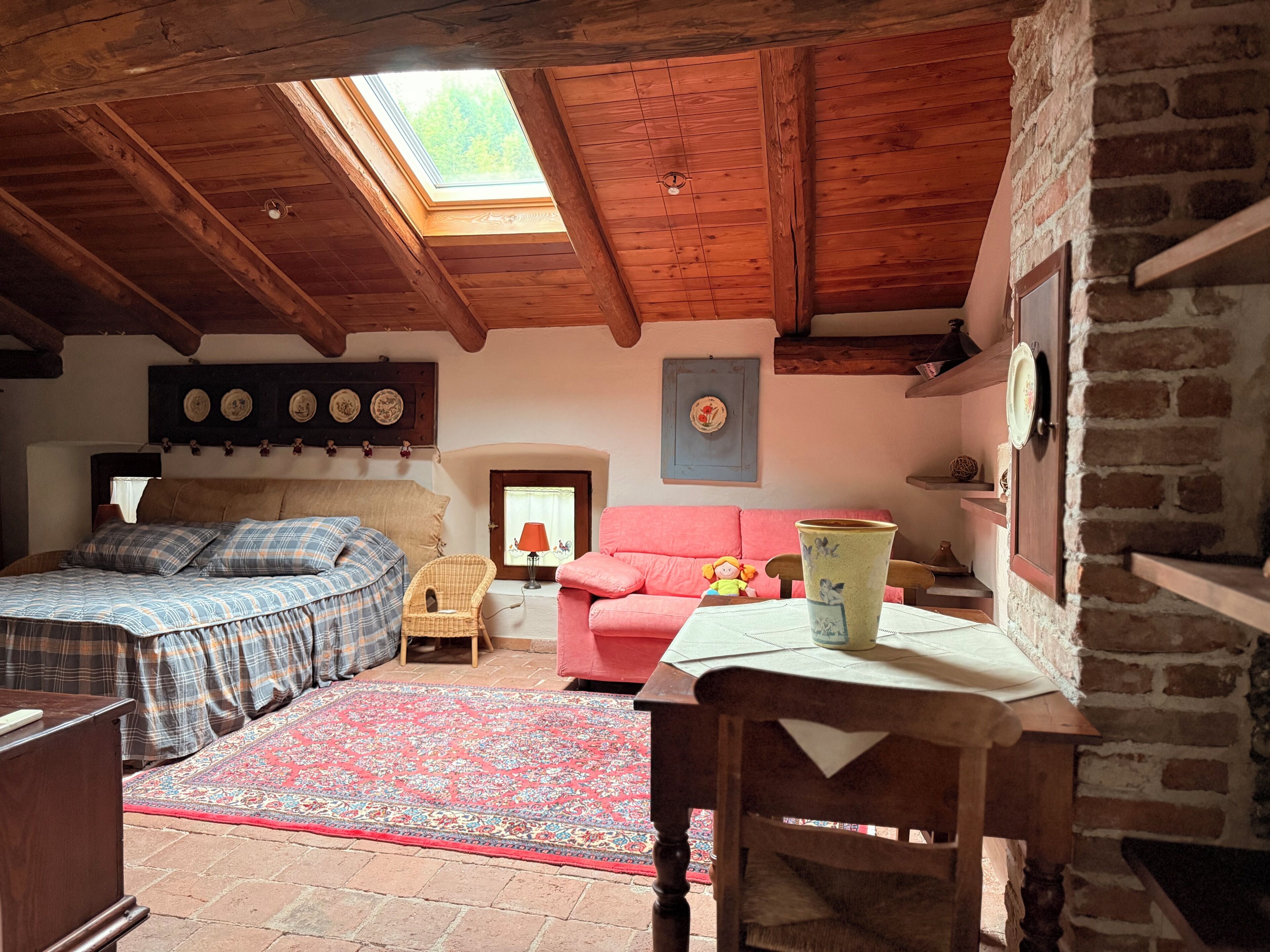 Une pièce confortable avec un lit, un canapé, une table, une cheminée et une lucarne.