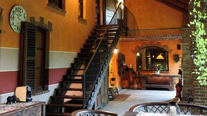 A cozy interior with a wooden staircase, a dining area with a table and chairs, and a clock on the wall.