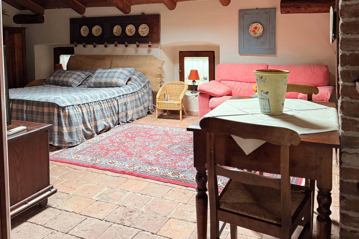 A cozy room with a bed, a chair, a table, and a skylight.