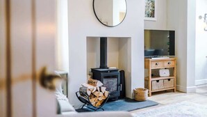 A cozy living room with a fireplace, a television, and a wooden cabinet. - NEW! Spacious 2-Bed Home, Amazing Location! (Chester)