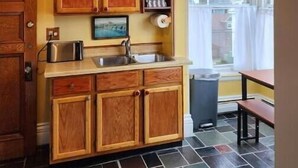 A compact kitchen with wooden cabinets, a built-in microwave, and a small window. - Island View House BnB Self Check-In # 4 / Free Off-Street Parking  (Portland)