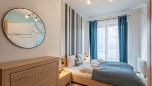 A modern bedroom with a bed, bedside tables, a dresser, a wall map, and a window with curtains.