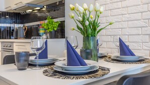 A dining table set with plates, glasses, and a vase of white tulips.