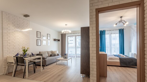 A modern living room with a dining area, a sofa, a coffee table, and a bed with a view.