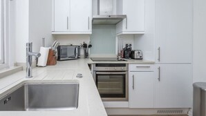 Una cocina moderna con armarios blancos, electrodomésticos de acero inoxidable y horno empotrado.