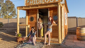 A wooden structure labeled "HIDEOUT" with a rustic design, featuring a small porch and a wooden barrel. - Large with King Beds, Movie & Game Room, Saloon & Close to Park (Yucca Valley)