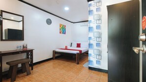 Una camera d'albergo con un letto, una scrivania, uno specchio, una sveglia e una porta.