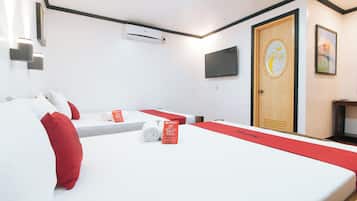 A hotel room with two beds, a TV, a door with a circular design, and a wall-mounted air conditioner.