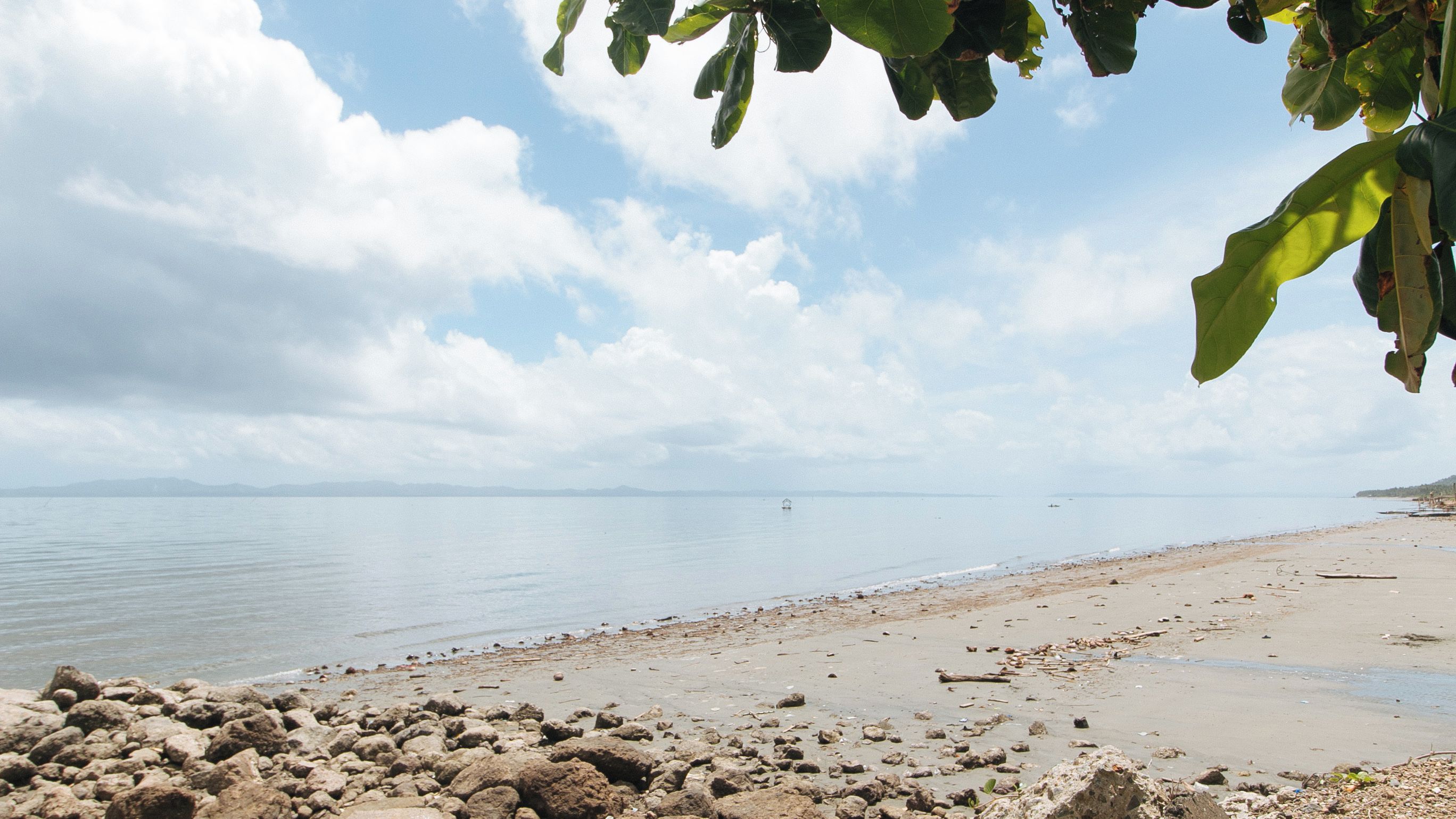 A beach with a rocky foreground and calm water.