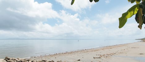 Una playa con primer plano rocoso y agua tranquila.
