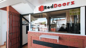 Une devanture de magasin avec une enseigne RedDoorz, une façade en briques et une vitrine où sont exposés divers articles.