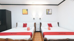 Ein Hotelzimmer mit zwei Betten, jeweils mit roter Decke und Kissen, sowie einem hölzernen Kleiderschrank.