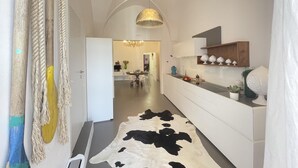 A modern kitchen with white cabinetry, a cowhide rug, and a hanging pendant light. - Casa Matilda in Fasano (Fasano)