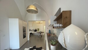 A modern kitchen with white cabinetry, a cowhide rug, a chandelier, and a white ceramic bowl on the counter. - Casa Matilda in Fasano (Fasano)
