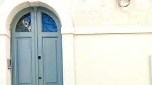 A light blue double door with a decorative glass window above it, set in a white wall with a simple archway. - Casa Matilda in Fasano (Fasano)