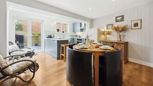Una cucina moderna con zona pranzo, pavimento in legno e vista all'esterno.