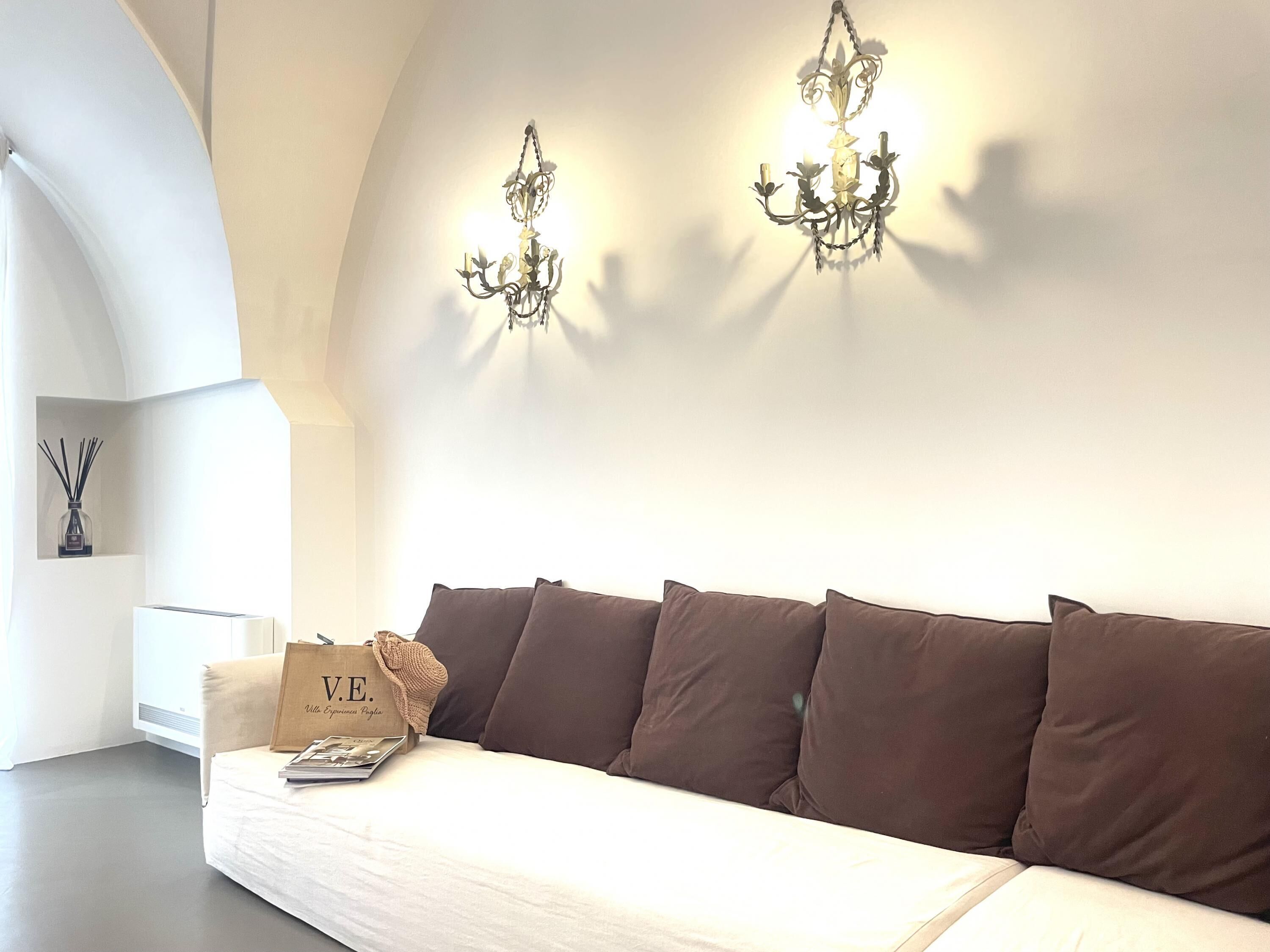 A modern living room with a white sofa, brown cushions, and a decorative bag on the armrest.
