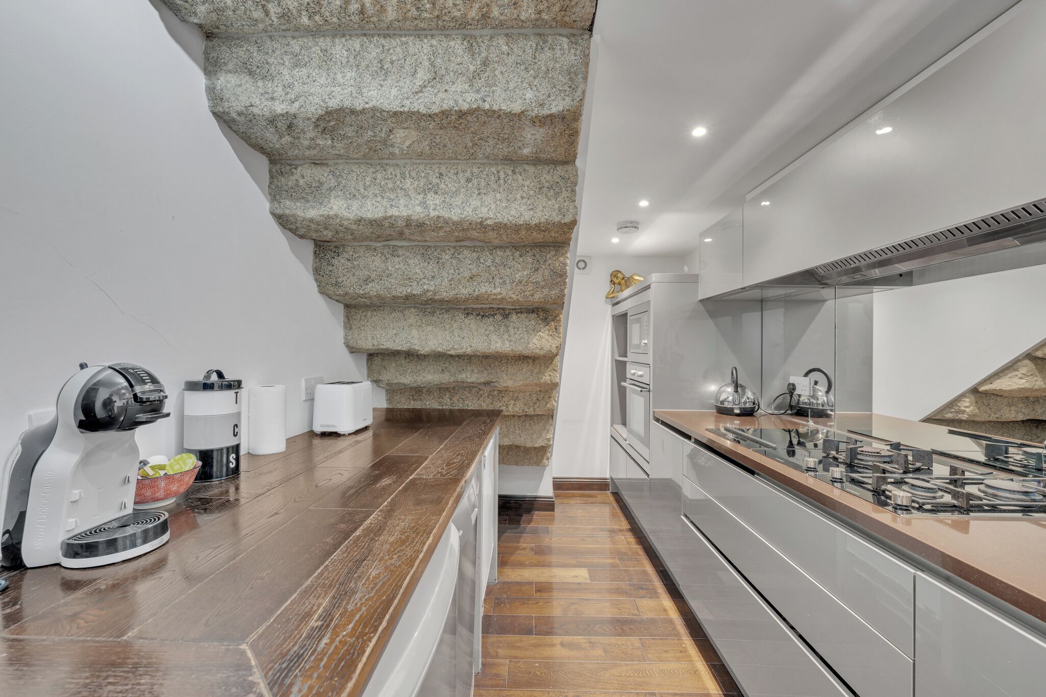 Een moderne keuken met een accentmuur van steen, een ingebouwde kookplaat en een houten aanrecht.