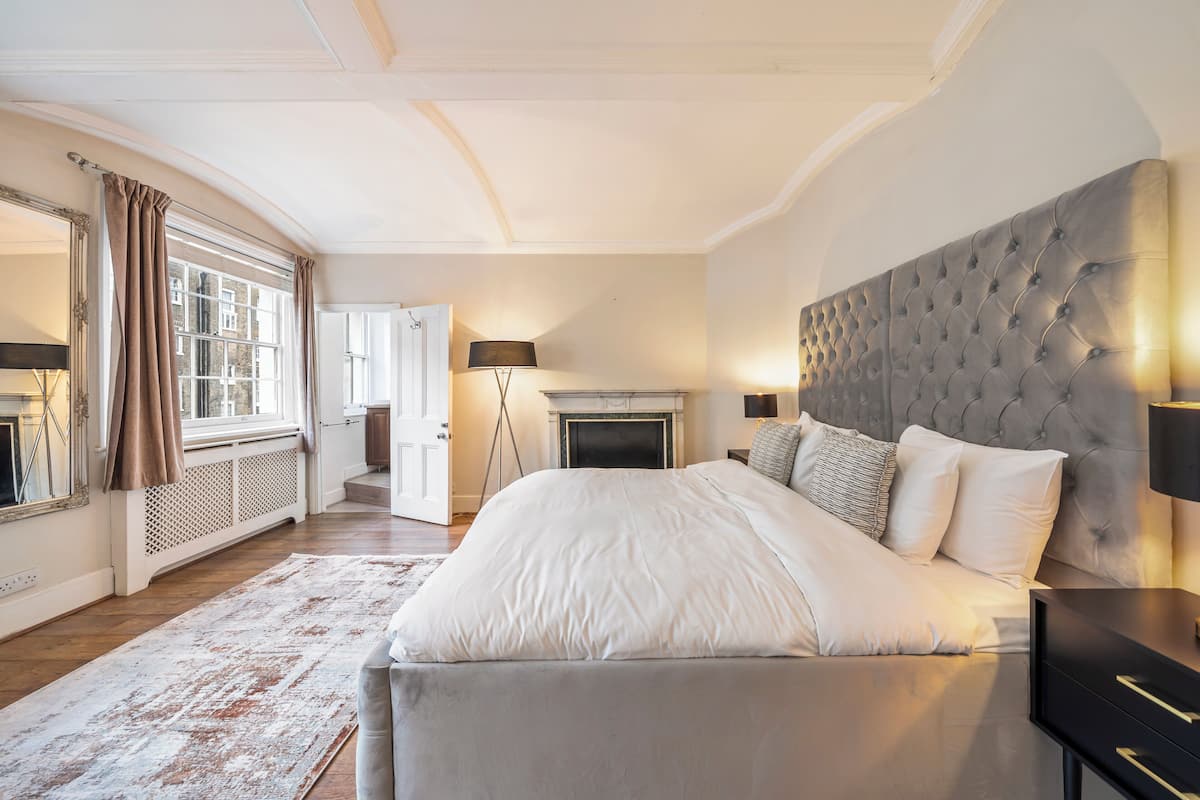 A spacious bedroom with a large bed, a fireplace, and a view of the outdoors through a large window.