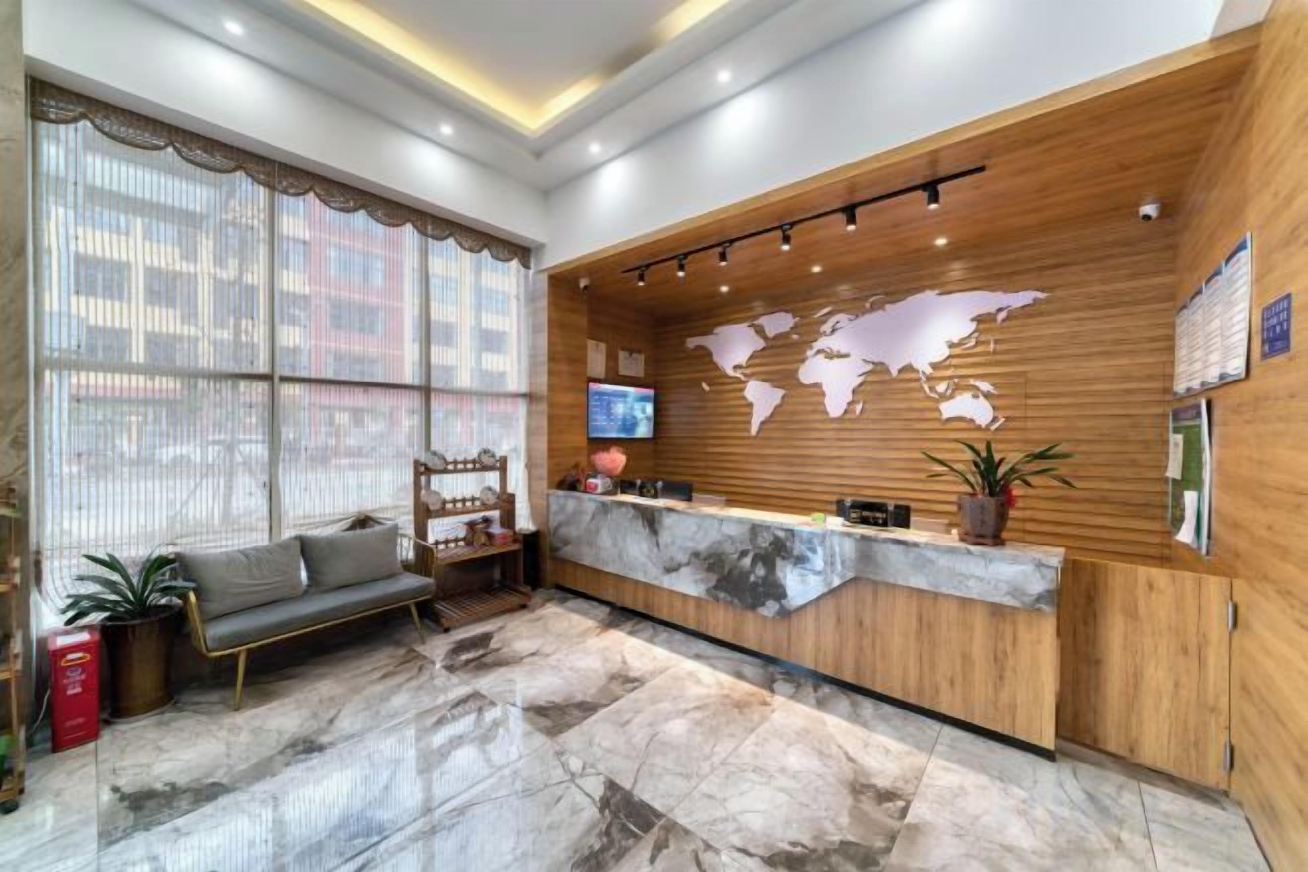 Un área de recepción con un mostrador de madera, un sofá, un mapa mundial y una pantalla de televisión.