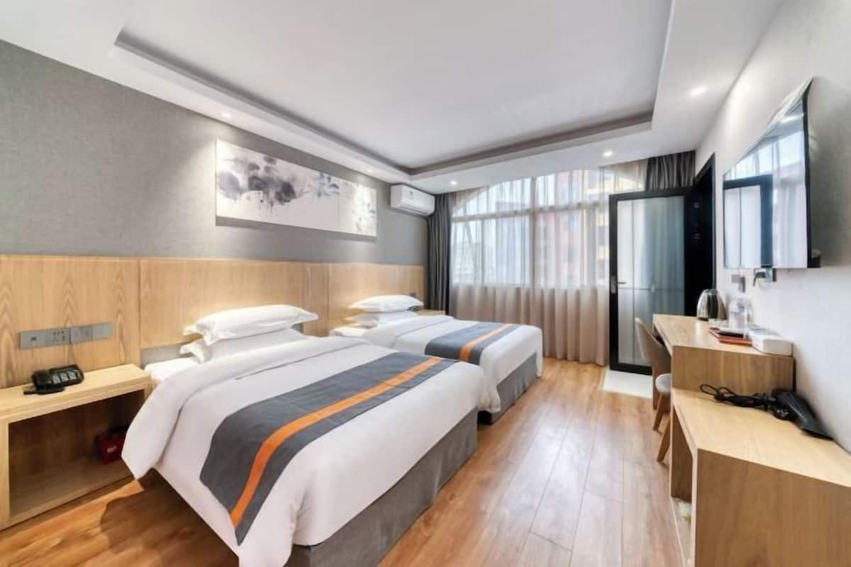 Une chambre d’hôtel avec deux lits, un bureau, une chaise, un téléphone et une télévision.