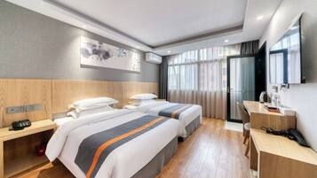 A hotel room with two beds, a desk, a chair, a telephone, and a television.