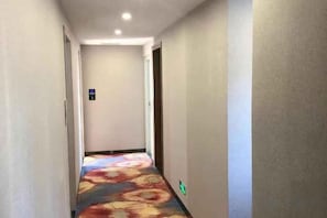 A hotel hallway with a carpeted floor and a door at the end.