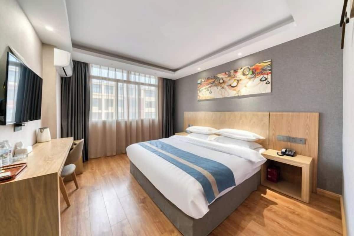 Une chambre d’hôtel moderne, dotée d’un grand lit, d’un bureau et d’une télévision.