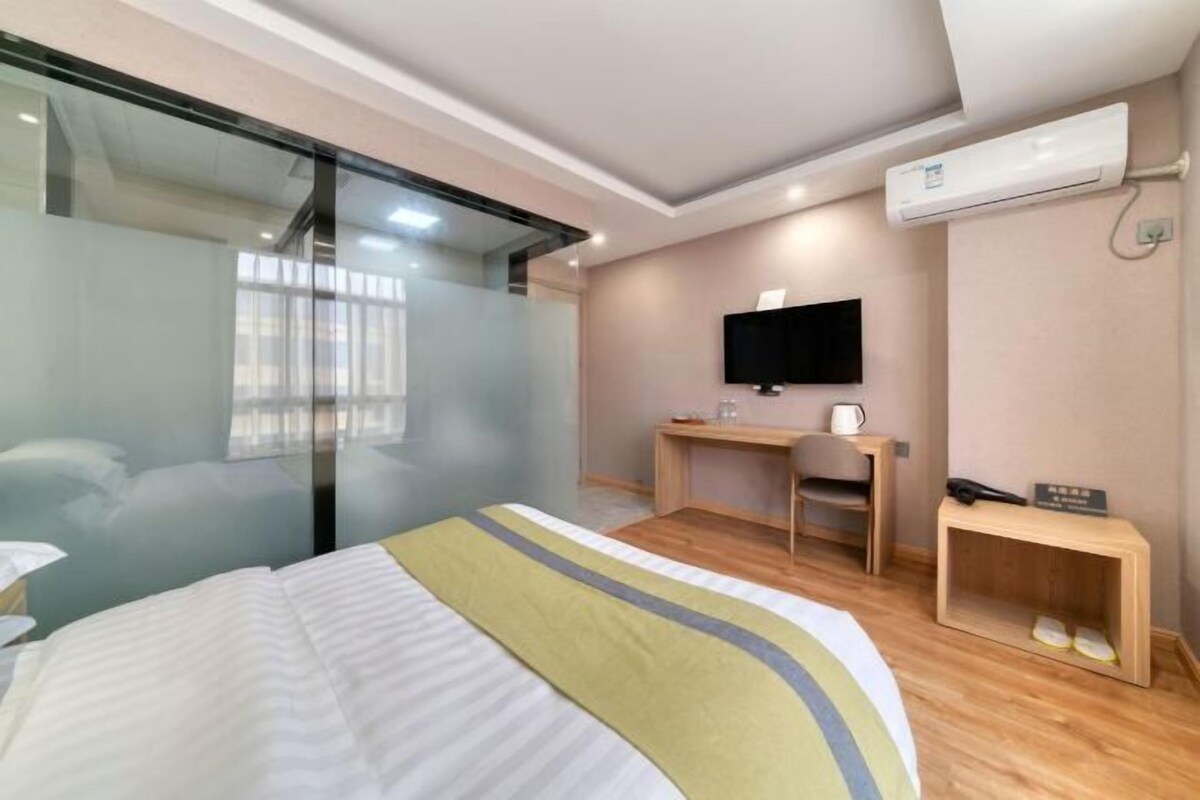 Une chambre d’hôtel équipée d’un lit, d’un bureau, d’une chaise, d’une télévision et d’un appareil de climatisation.