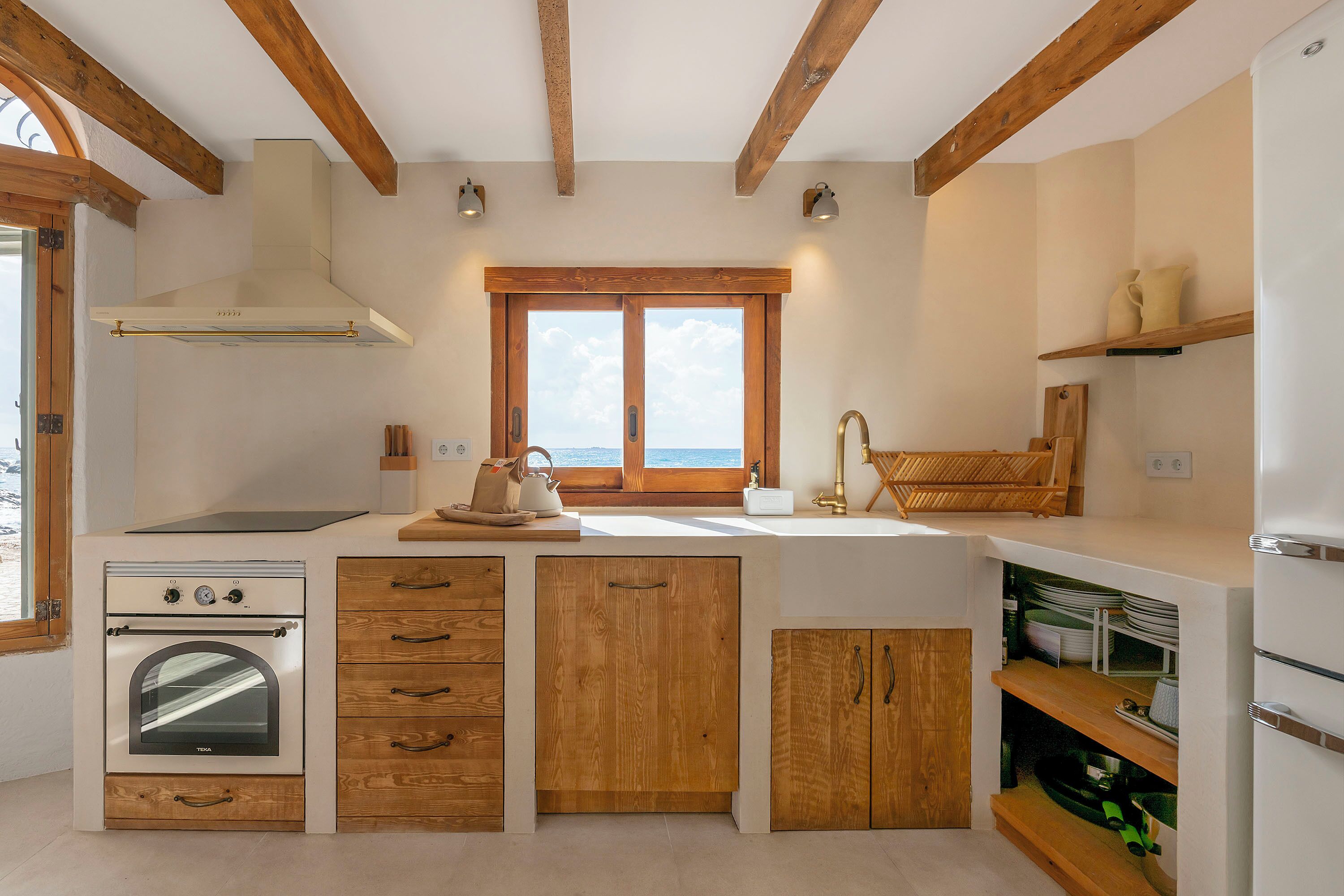 A kitchen with wooden cabinets, a built-in oven, a window, and a sink.