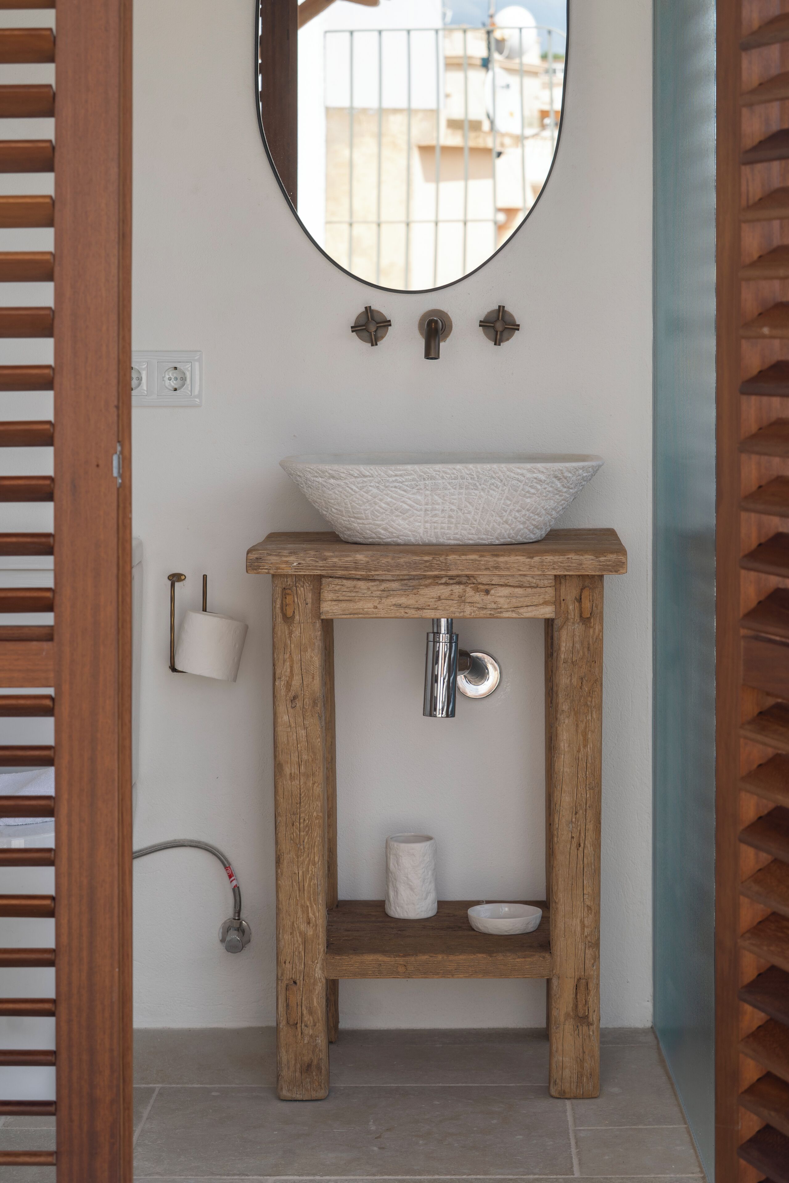 A bathroom with a wooden vanity, a round mirror, and a white sink.