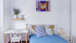 A bedroom with a bed, a desk, a chair, and a wall-mounted shelf with a plant. - Bright Apartment in Marseille (Marseille)