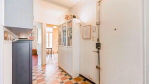 A hallway with a checkered floor, a door with a lock, and a cabinet with a light fixture. - Bright Apartment in Marseille (Marseille)