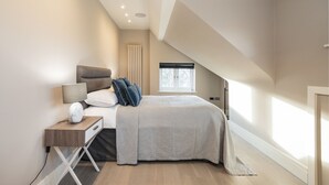 A modern bedroom with a bed, bedside table, lamp, and a window. - Hampstead Lux Flat-Hosted by Sweetstay (London)