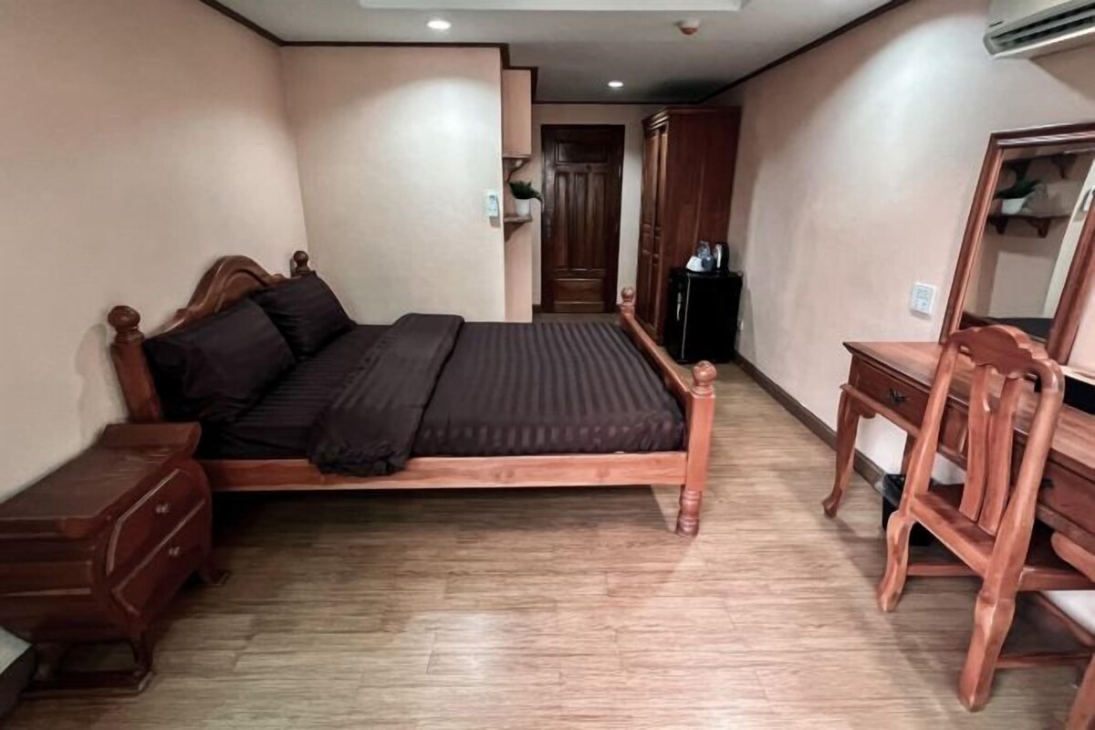 A bedroom with a wooden bed, a nightstand, a dresser, a mirror, and a wardrobe.