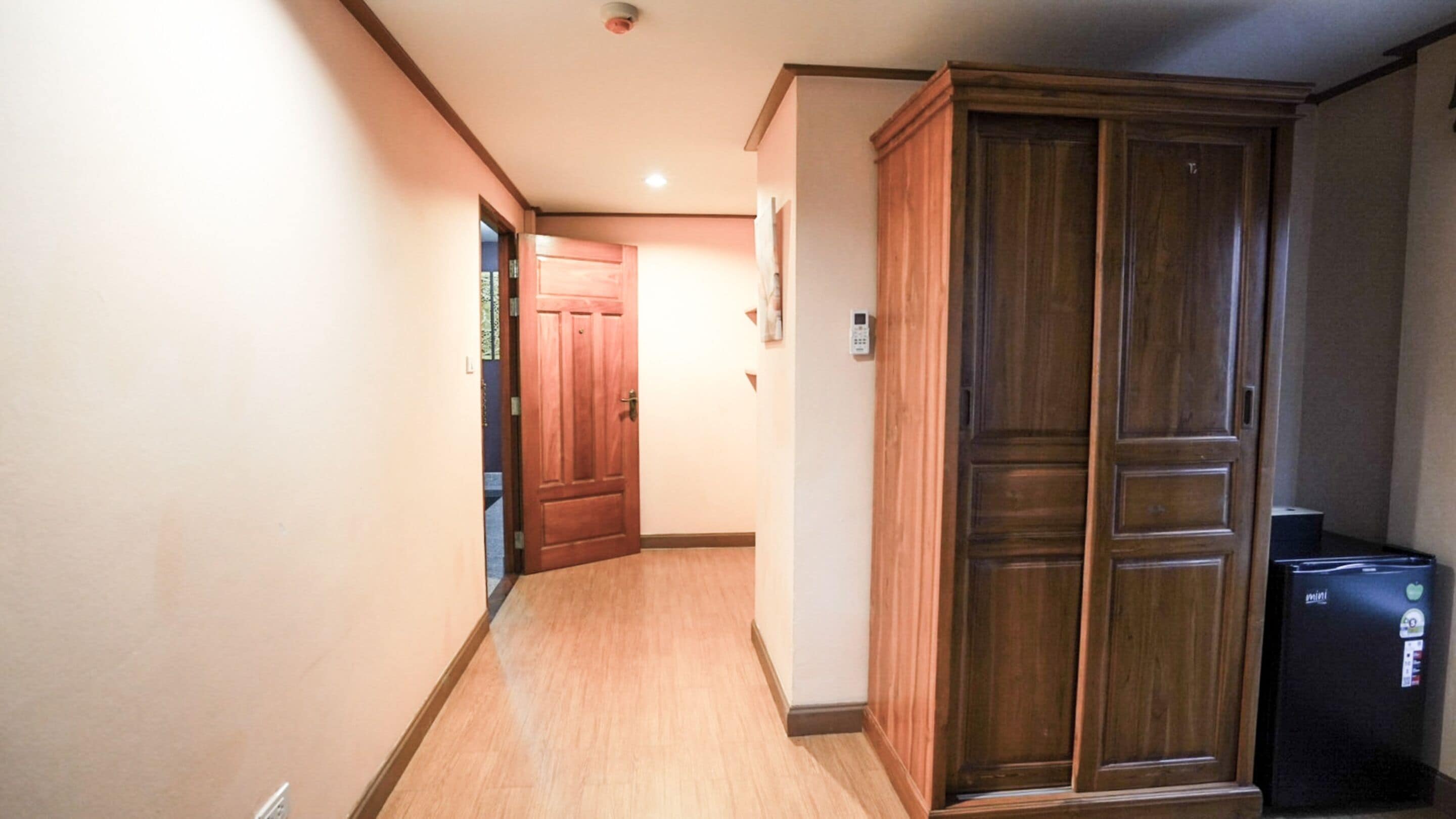 A hallway with wooden flooring, a wooden wardrobe, and a black printer.