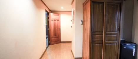 A hallway with wooden flooring, a wooden wardrobe, and a black printer.