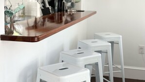 A kitchen with a wooden countertop, white stools, and a white backsplash. - 2 Bedroom/2 Bath In the Heart of Newport- Deck + Back Yard + Off-Street Parking! (Newport)
