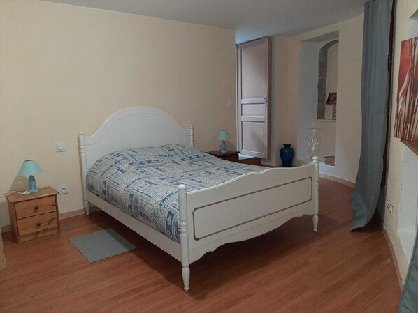 Ein Schlafzimmer mit einem Einzelbett, einem Nachttisch, einer Lampe und einer Vase auf einer Kommode.